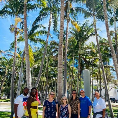 a group of people standing next to a palm tree