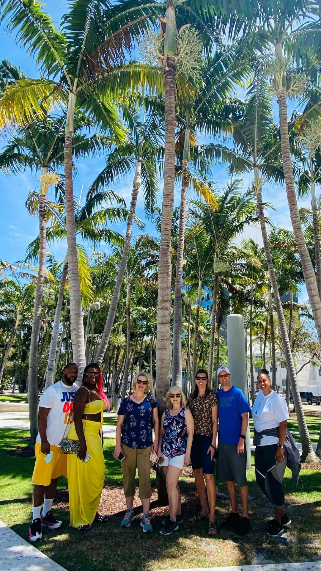 a group of people standing next to a palm tree
