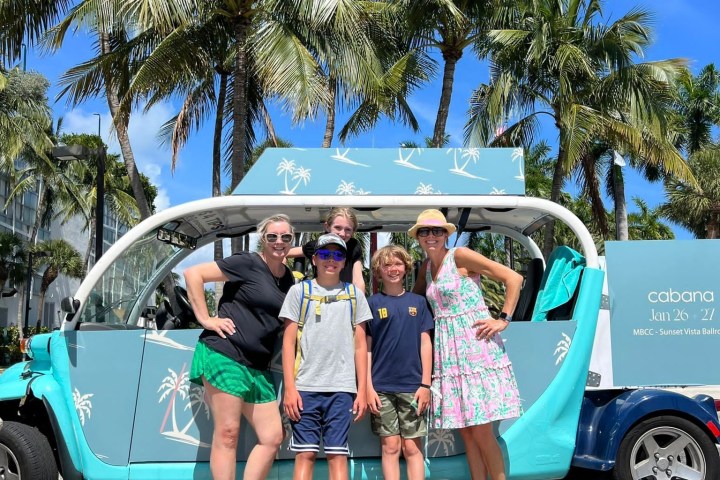 a group of people standing in front of a car posing for the camera